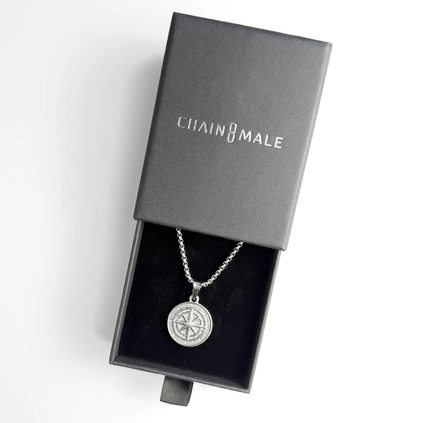 Silver stainless steel compass pendant necklace in a black Chain Male jewellery box on a white background