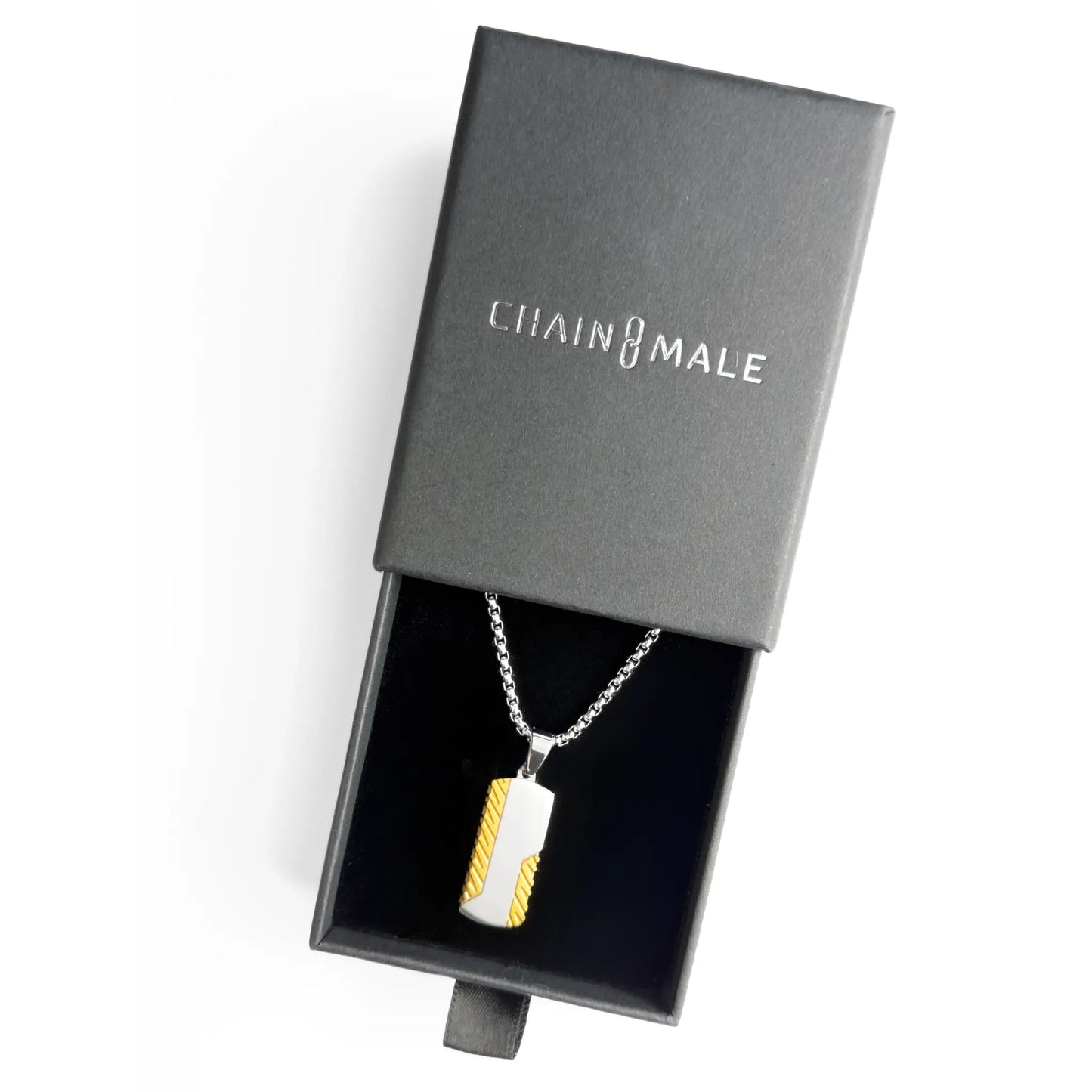 Gold and silver dog tag pendant necklace in a black Chain Male jewellery box on a white background