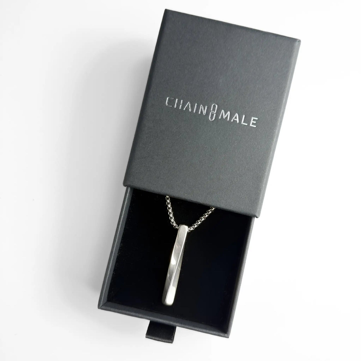 Silver stainless steel bar pendant necklace in a black Chain Male jewellery box on a white background