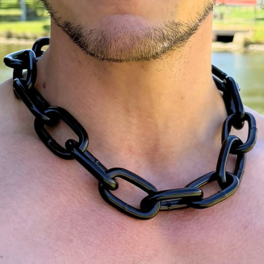 Close-up of a Big Black Chain Extra Thick necklace worn on a bare chest with park in background