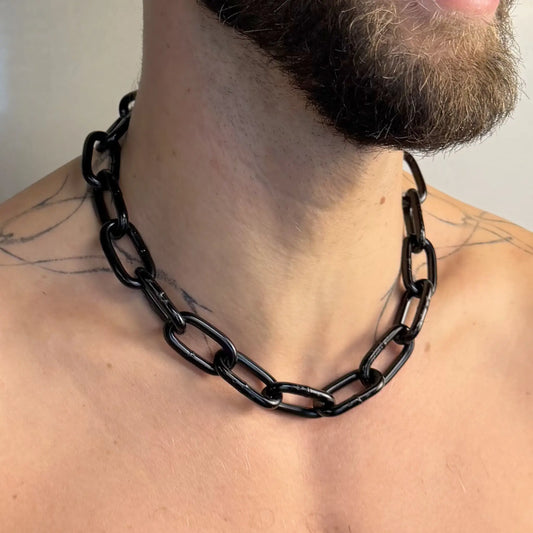 Close-up of a Big Black Chain necklace worn on a bare tattooed chest