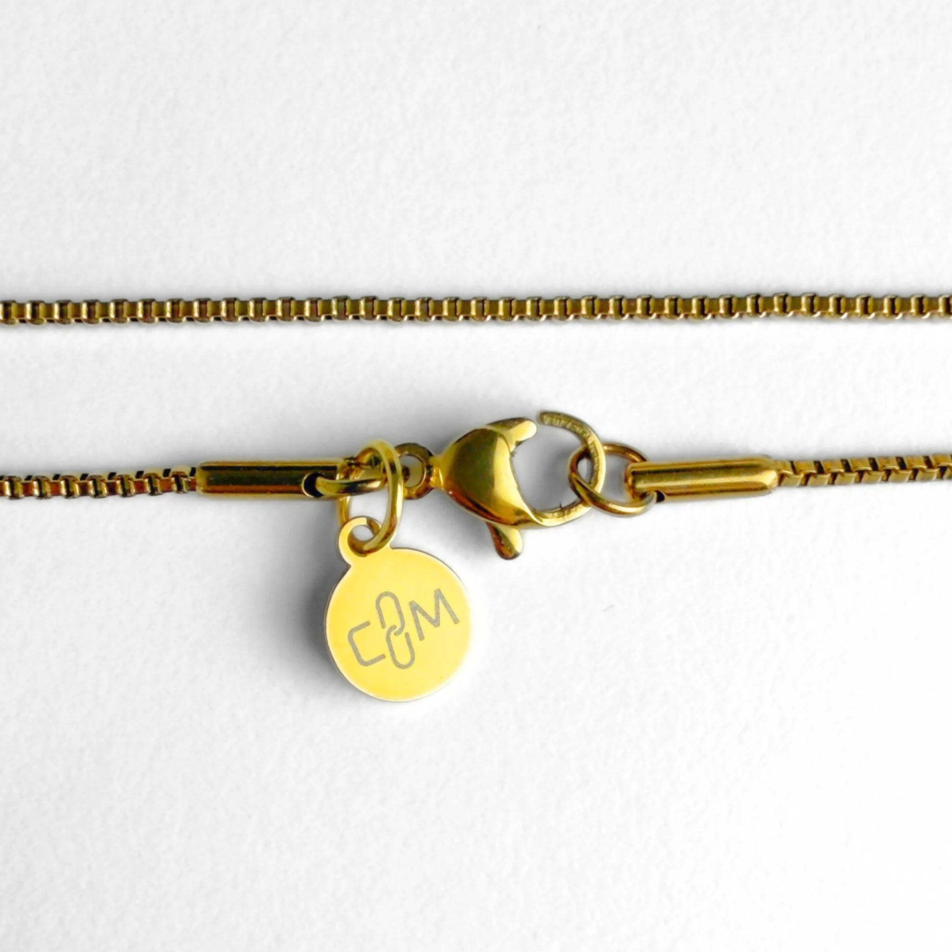 Chain Male gold 1.2mm box chain necklace flat lay with CM charm, fine 18ct gold plated men's Everyday collection