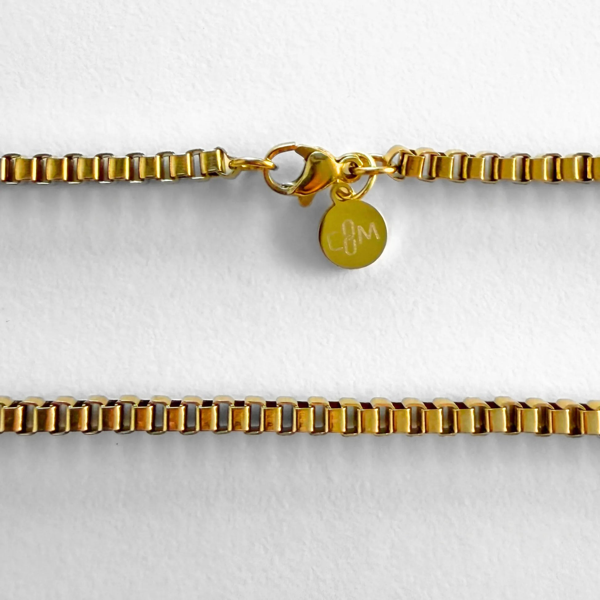 Chain Male gold 3mm box chain necklace flat lay with CM charm, 18ct gold plated men's Everyday collection