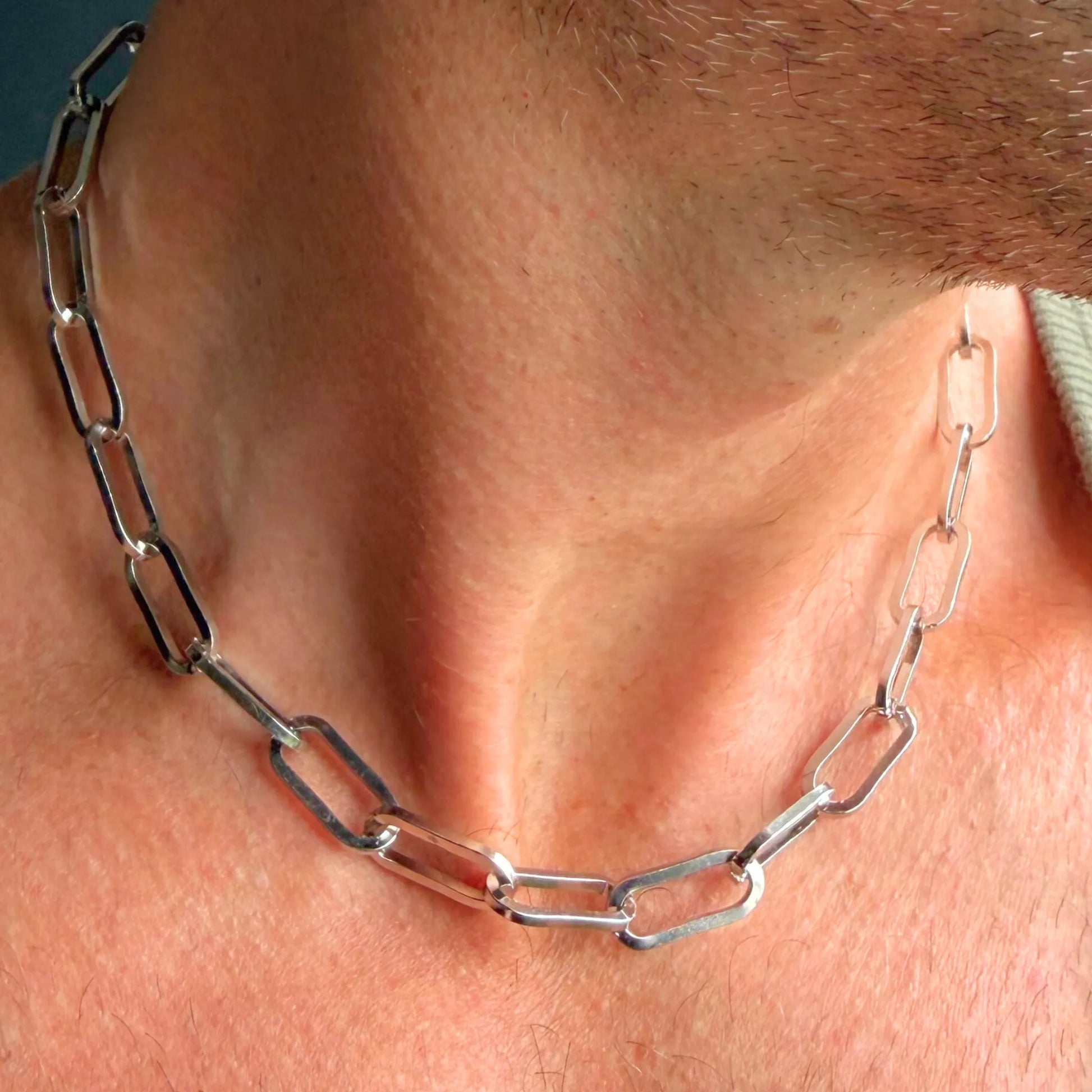 Chain Male silver paperclip choker necklace close-up, oversized rectangular link stainless steel men's jewellery