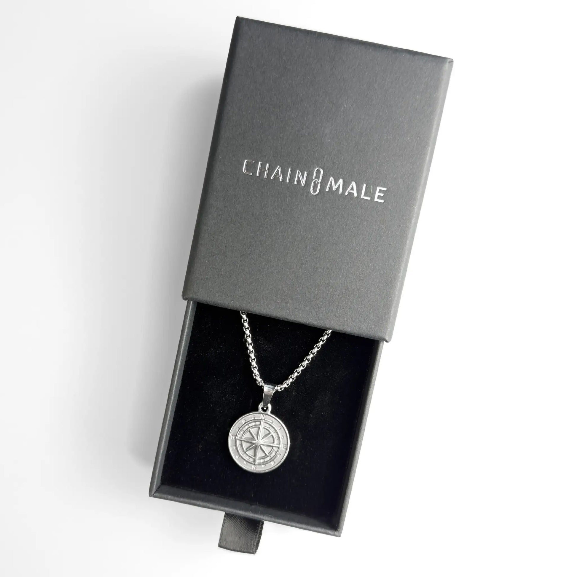 Silver stainless steel compass pendant necklace in a black Chain Male jewellery box on a white background
