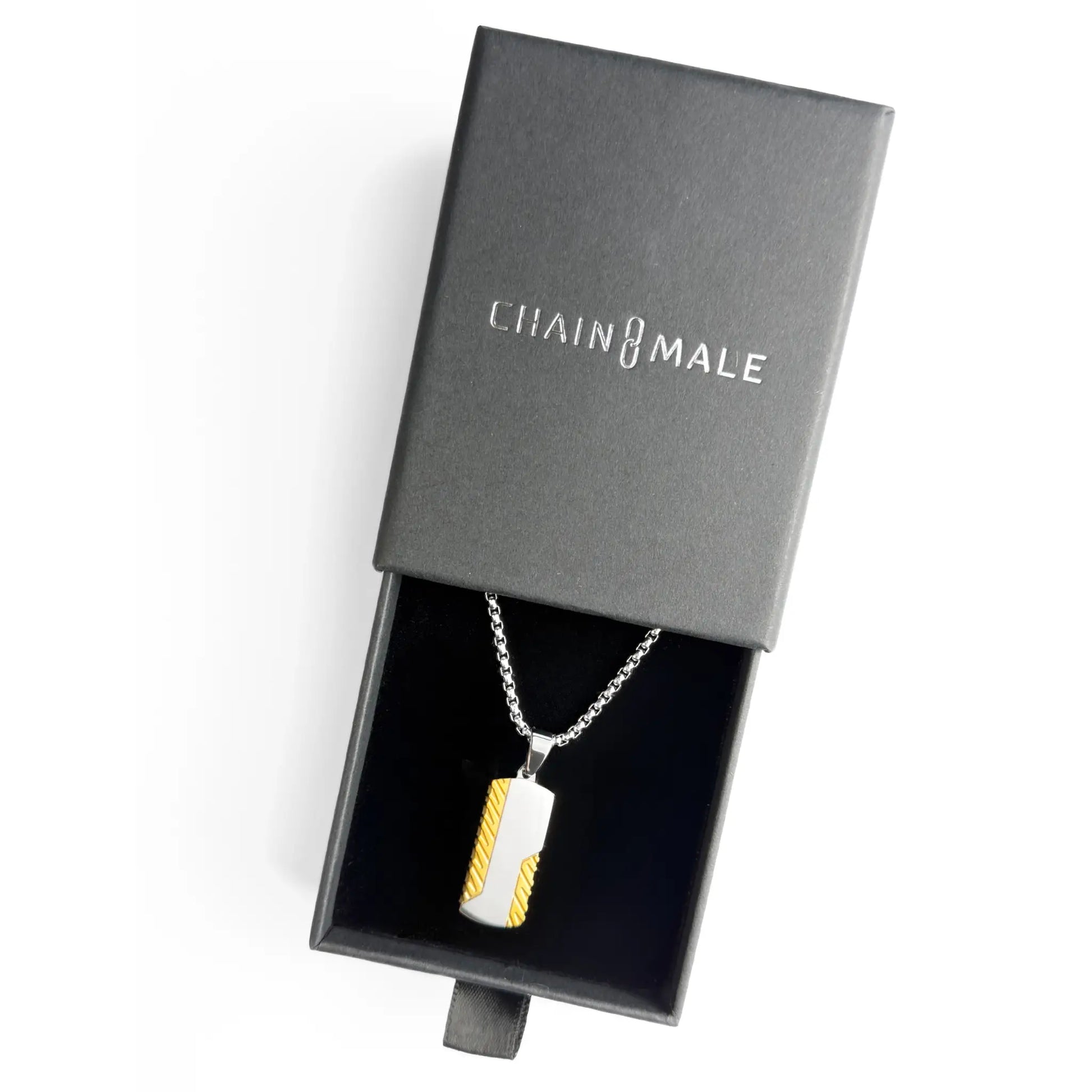 Gold and silver dog tag pendant necklace in a black Chain Male jewellery box on a white background