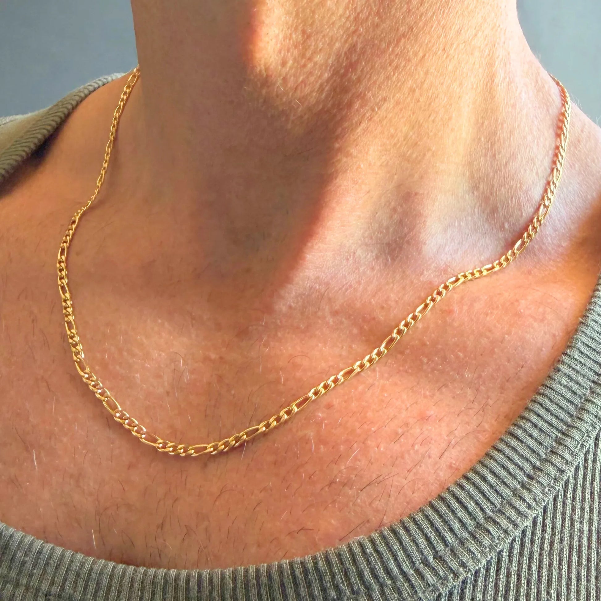 Chain Male gold 3mm Figaro chain necklace close-up worn with singlet, 18ct gold plated alternating link men's jewellery