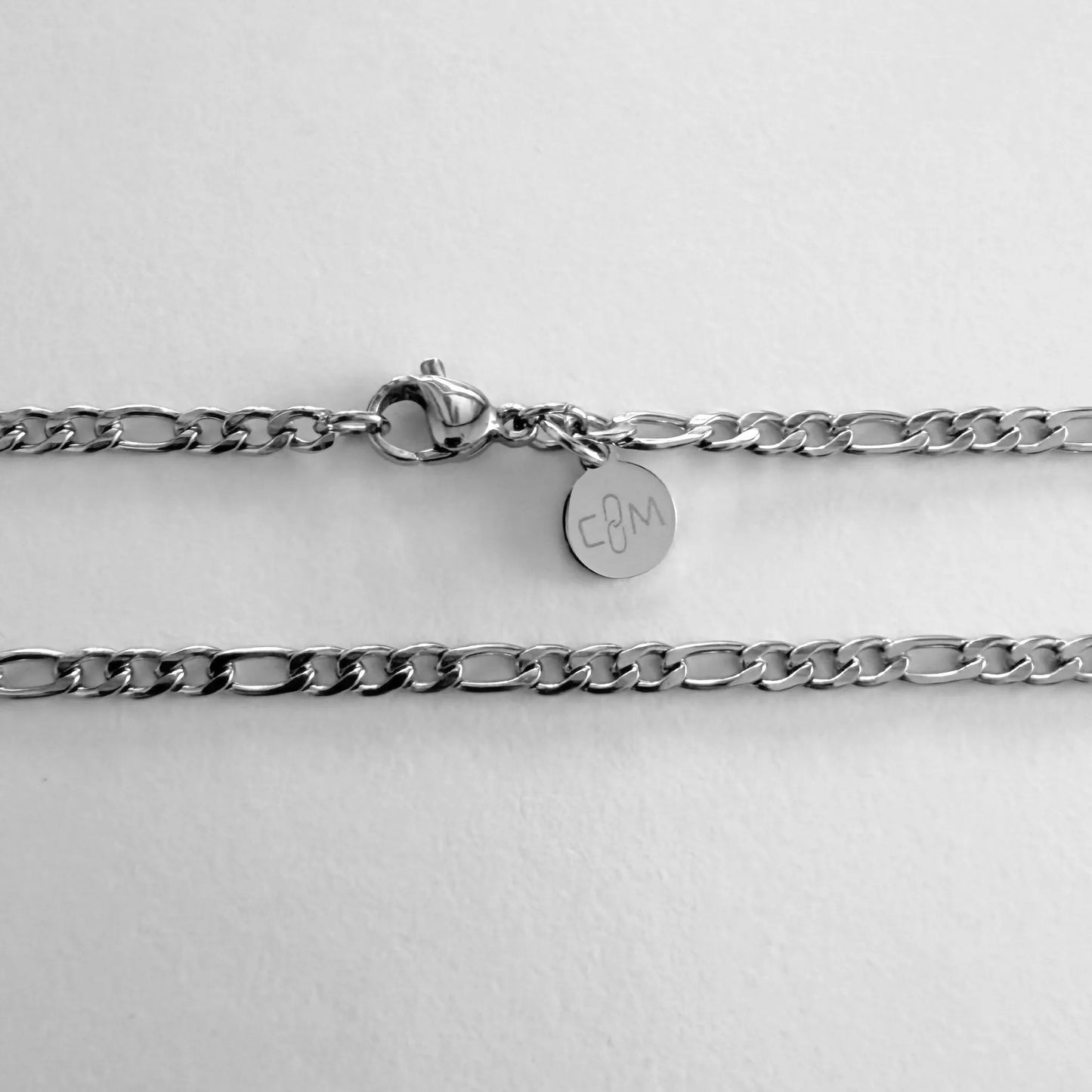 Chain Male silver 3mm Figaro chain necklace flat lay with CM charm, stainless steel men's Everyday collection