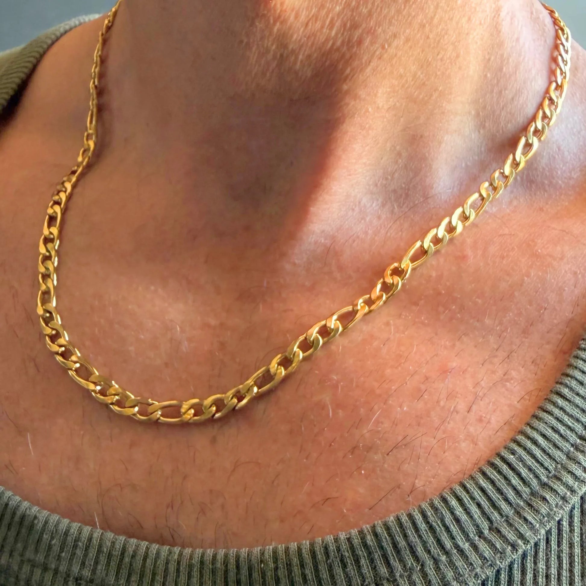 Chain Male gold 5mm Figaro chain necklace close-up worn with singlet, bold 18ct gold plated alternating link men's jewellery