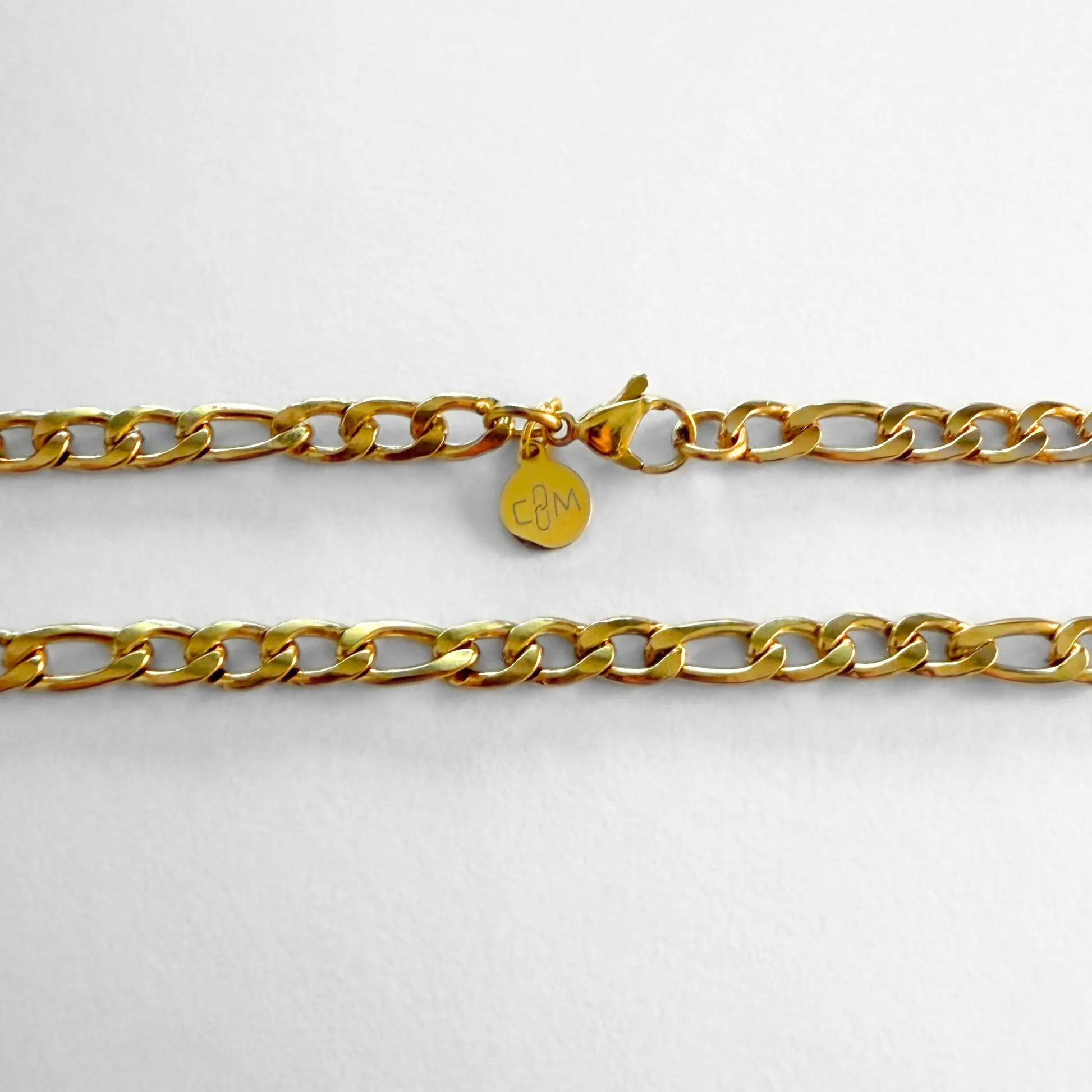 Chain Male gold 5mm Figaro chain necklace flat lay with CM charm, 18ct gold plated men's Everyday collection