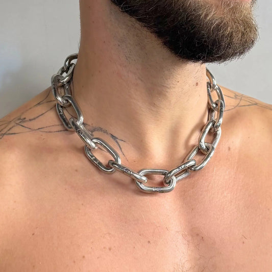 Close-up of a heavy duty stainless steel chain necklace on a tattooed bare chest