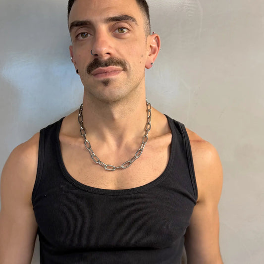 Man wearing a light duty stainless steel chain necklace in a black singlet with piercings and moustache