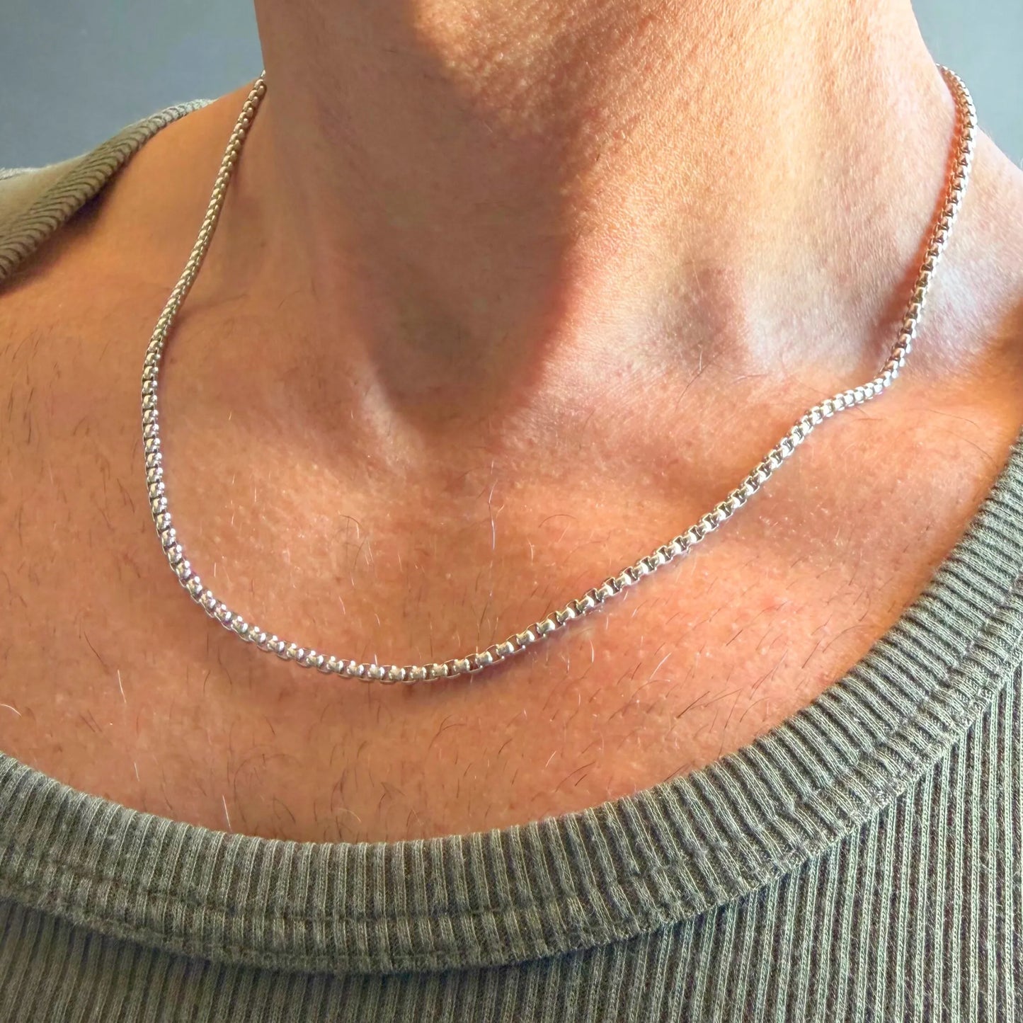 Chain Male silver rolo chain necklace close-up worn with singlet, rounded interlocking link stainless steel men's jewellery