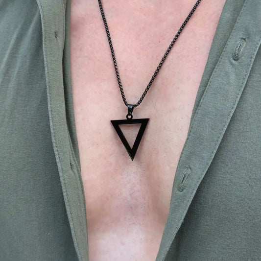 Close up of a black pendant necklace worn by a man with a green button shirt