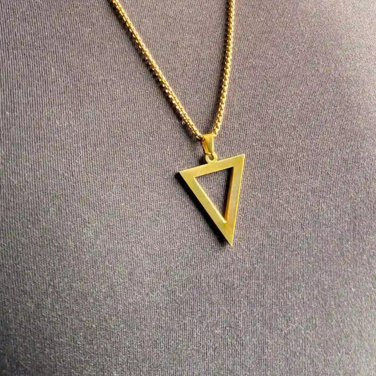 Close up of a gold triangle pendant necklace worn over a black tshirt