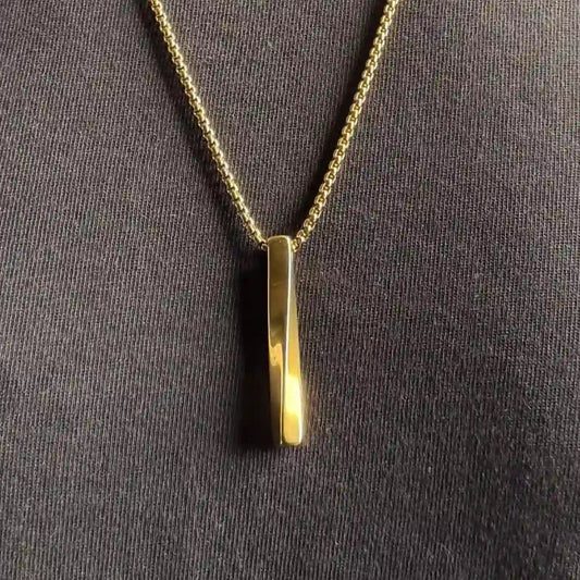 Close up of a gold plated stainless steel bar pendant necklace worn over a black tshirt